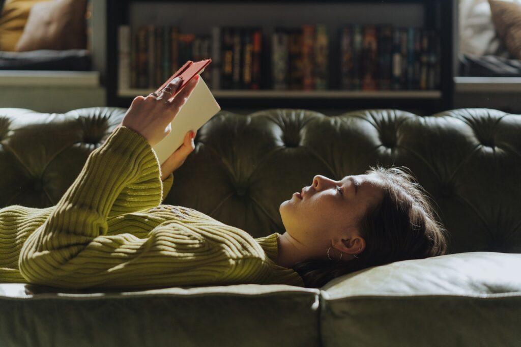 Eine Frau liest ein Buch auf einem Sofa