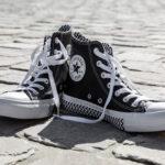 Bild eines Paares All Star Converse Sneakers auf einer Straße mit Kopfsteinpflaster.